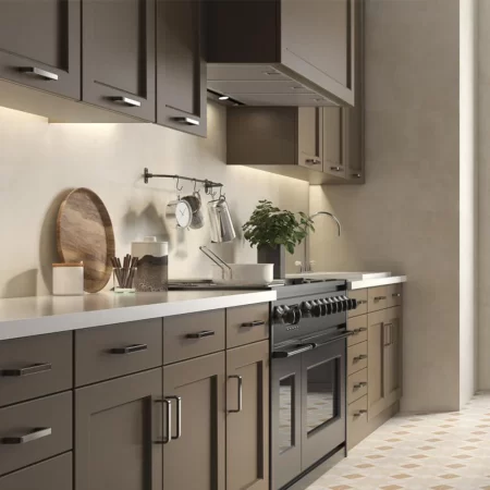 Modern kitchen interior featuring Eleganza Beige 333x1000mm wall tiles by Pamesa Ceramica. The beige concrete-effect tiles create a sleek, seamless backdrop behind dark brown cabinets, a stainless steel oven, and minimalist décor, enhancing the space with a warm and contemporary look.